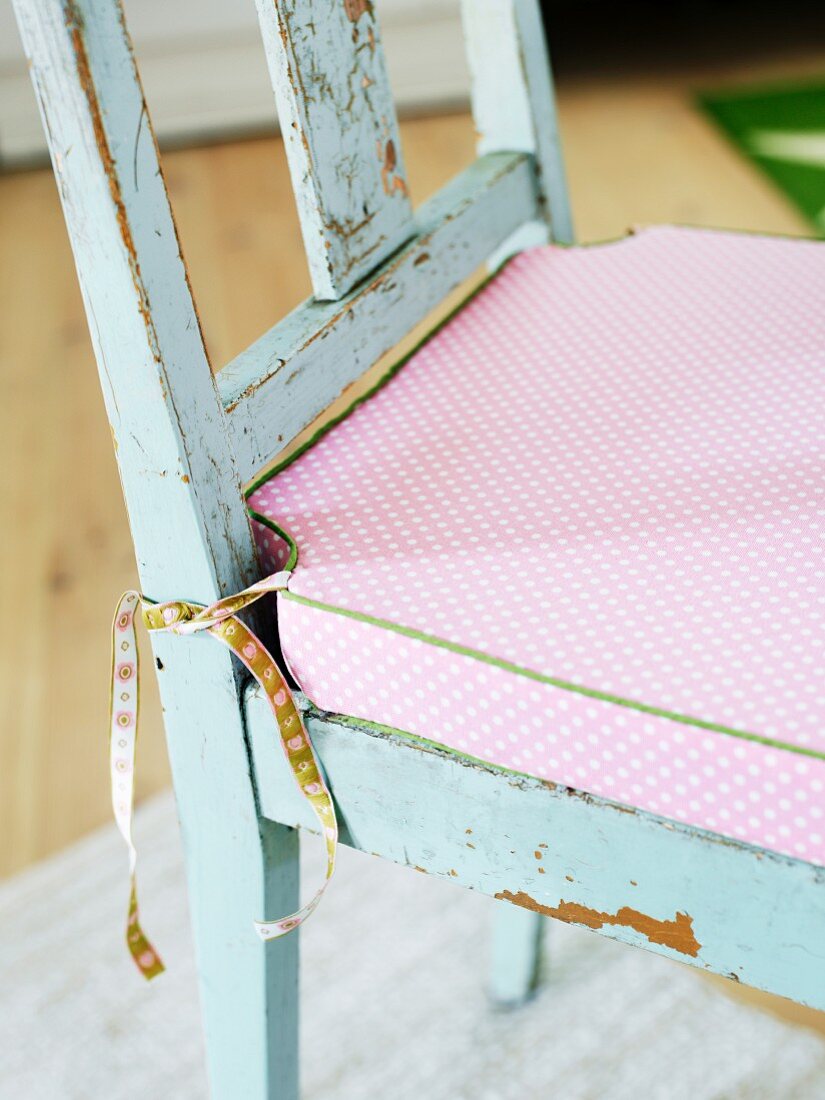 Rosa Sitzkissen im romantischen Landhausstil auf abgenutztem Küchenstuhl