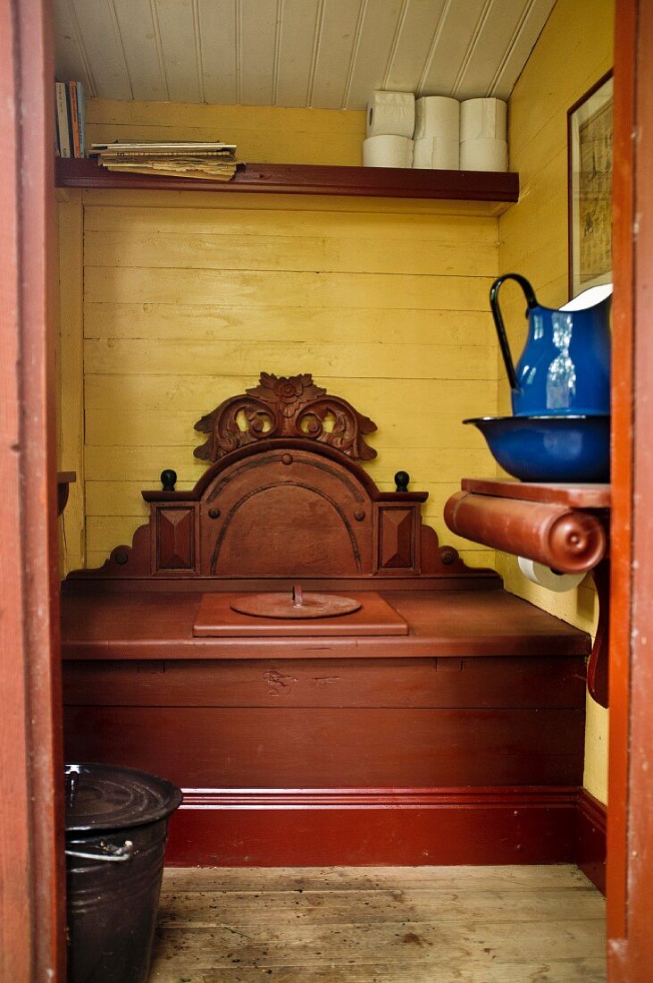 Outhouse with carved wooden privy and blue enamel pitcher and basin