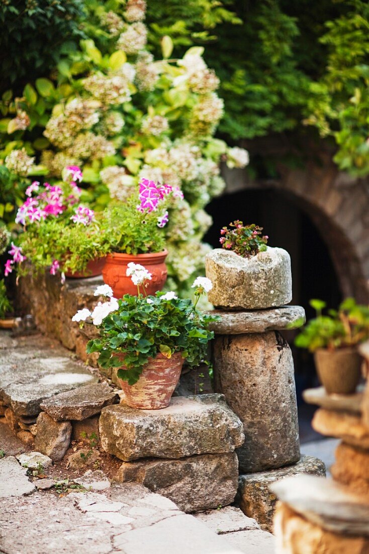 Blumentöpfe als Deko auf kleiner Natursteinmauer