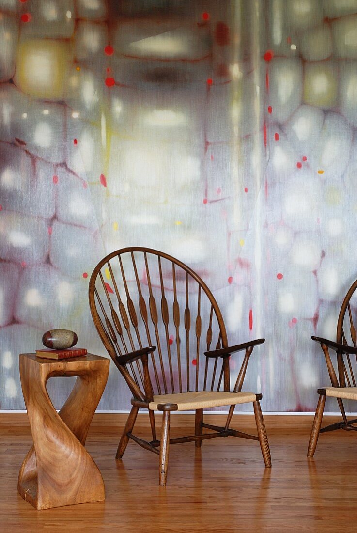 Pfauenstühle und kunstvoll gestalteter Beistelltisch aus Edelholz vor pastellfarbener Wandgestaltung
