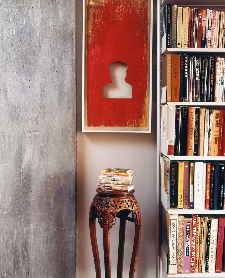 Objet d'art and antique wooden stand between exposed concrete slab and bookcase