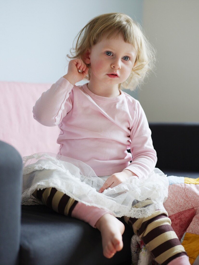 Little girl wearing tulle skirt sitting on armchair