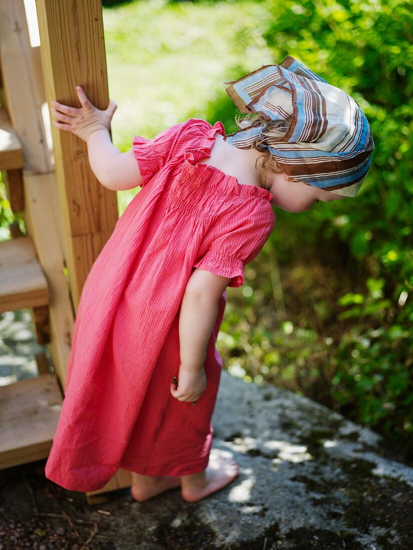 Kleines Mädchen in Sommerkleid erkundet moosbewachsenen Boden