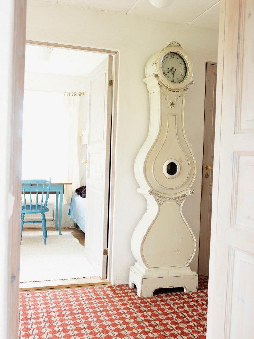 Antique, white longcase clock in tiled hallway