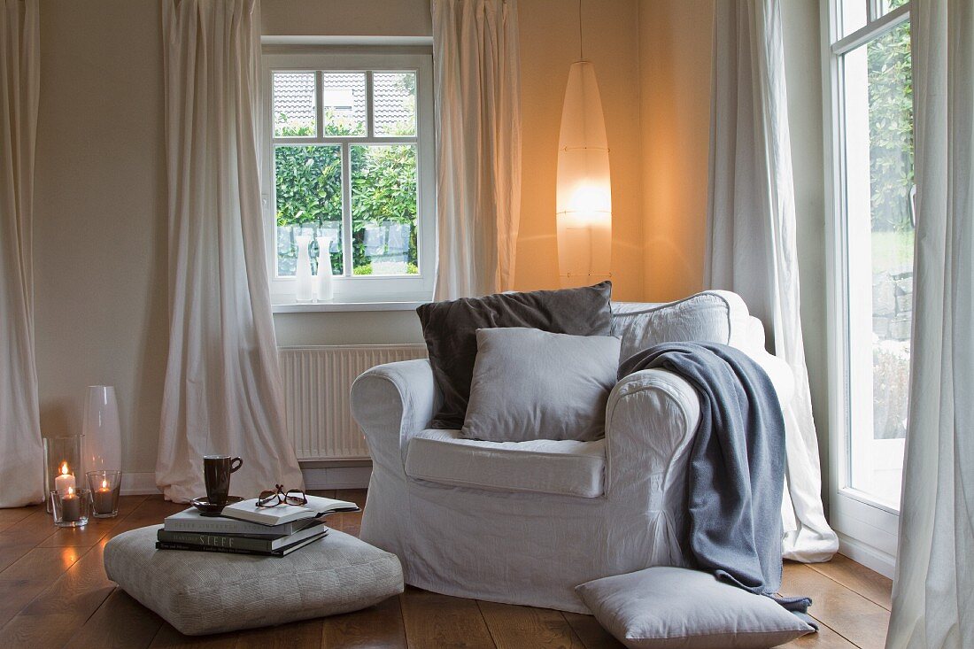 Wohnzimmerecke mit gemütlichem Sessel, Bodenkissen und ellipsenförmiger Lampe
