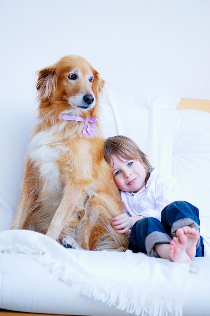 Kleines Mädchen mit Hund auf weisser Couch