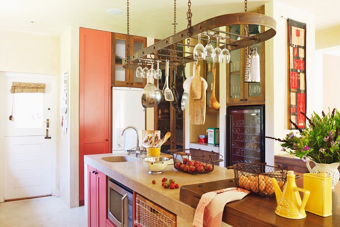 Moderne Landhausküche mit hängenden Küchenutensilien über der Kücheninsel