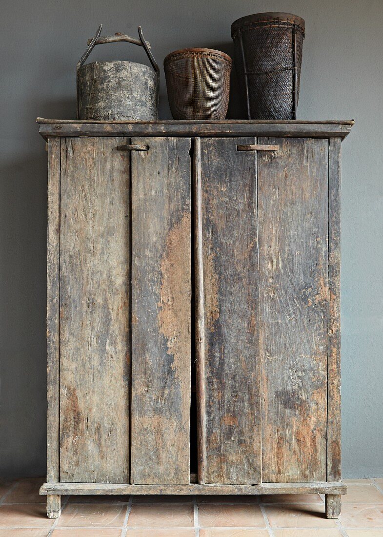 Old vessels on top of rustic cupboard against grey wall