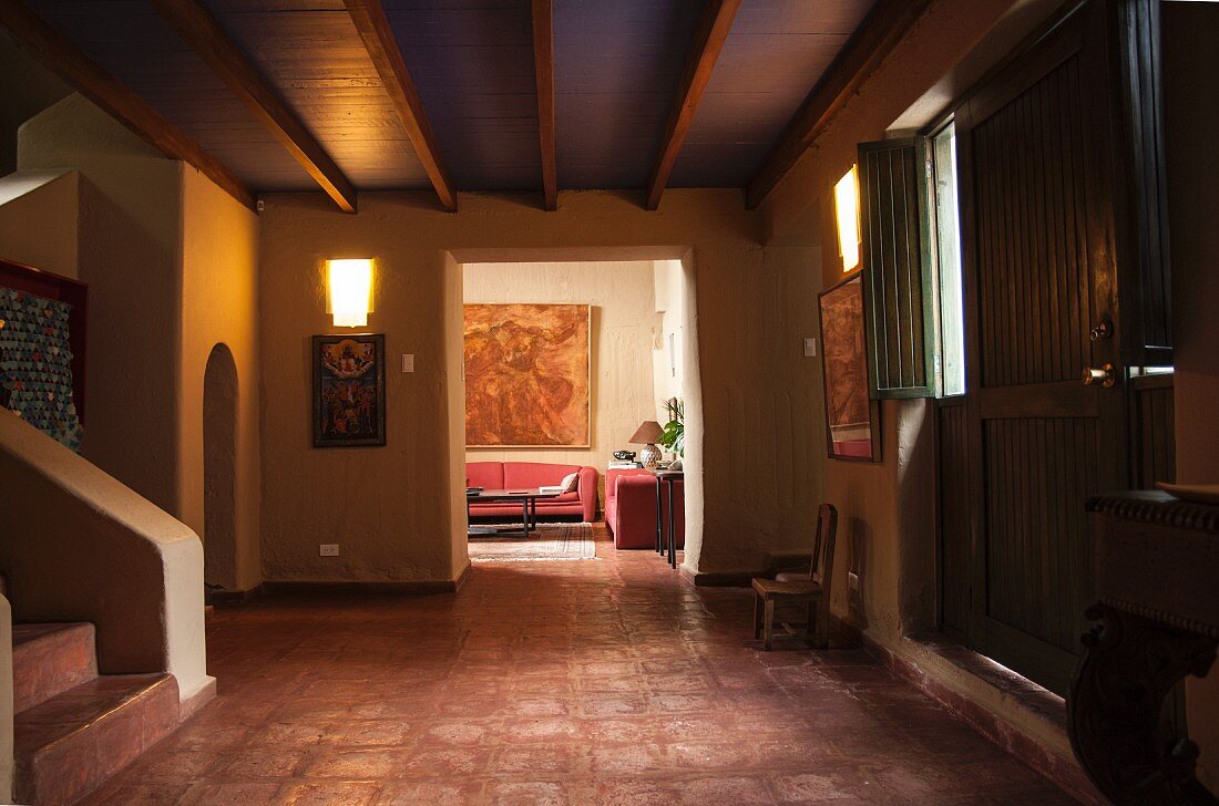 Große, dunkle Diele mit Terrakottfliesen, Holzbalkendecke und mit Blick ins Wohnzimmer
