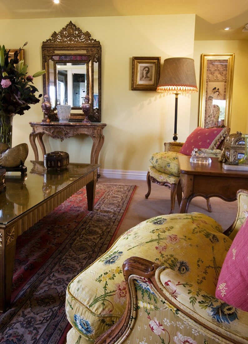 Gelbes Wohnzimmer im Barockstil mit prunkvollem Wandspiegel und vergoldetem Couchtisch mit Glasplatte