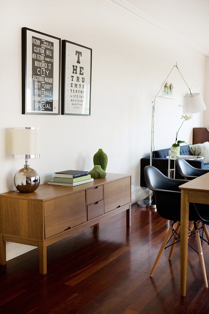 Offener Wohnraum mit Sideboard im Retrolook und schwarzen Eames-Stühlen am Esstisch