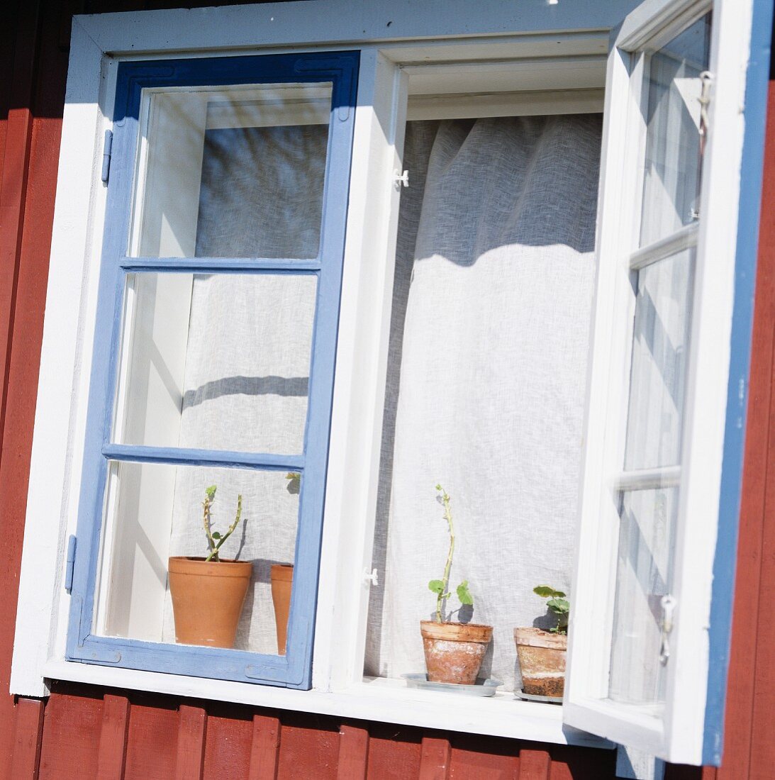 Offenes Fenster eines traditionellen, schwedischen Hauses im Sonnenlicht