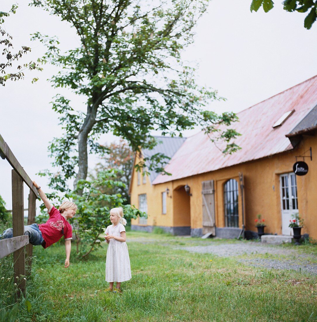 Kinder vor einem traditionellen, schwedischen Haus im Garten spielend