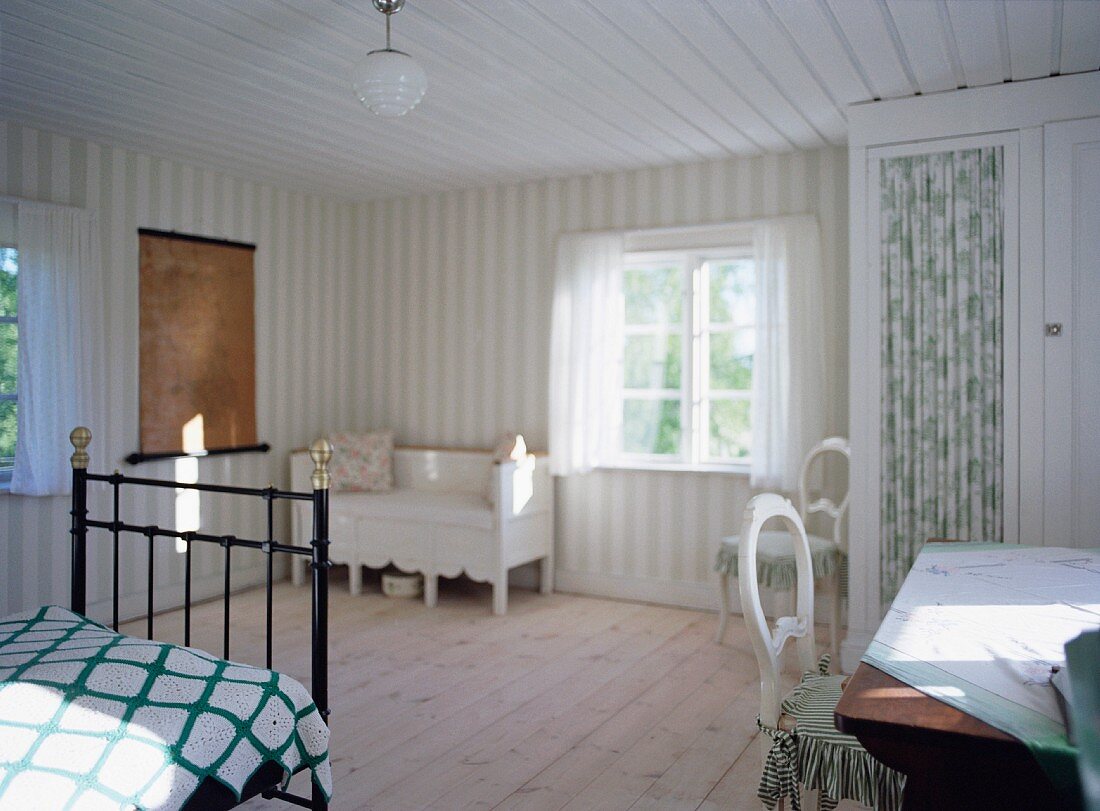 Geräumiges, helles Schlafzimmer mit einfachem Holzdielenboden und weisser Sitzbank