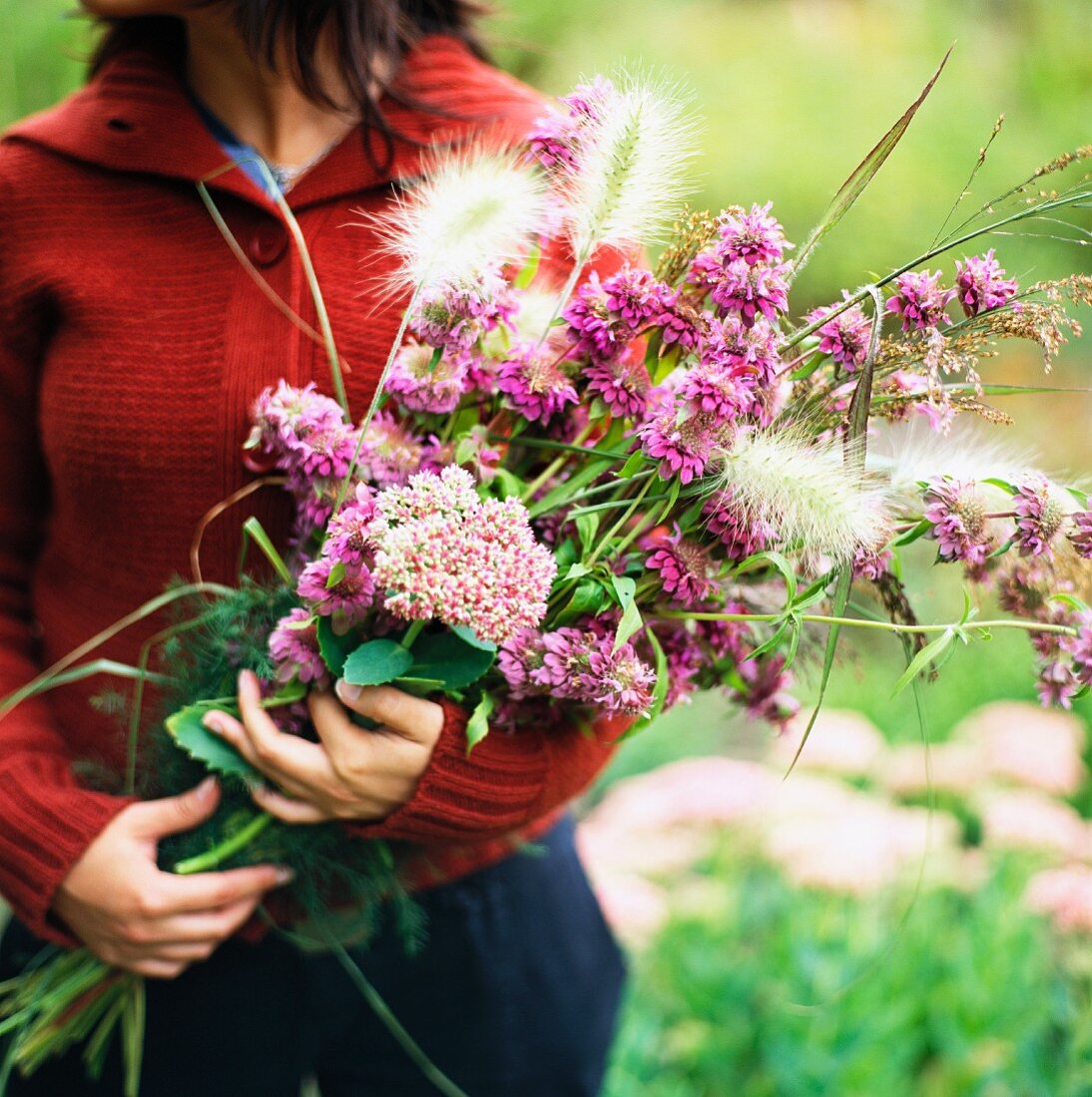 A woman holding a bouquet of purple flowers.