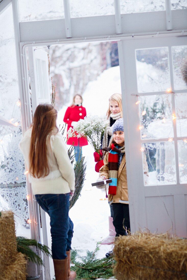Mädchen in Tür stehend empfängt Gäste mit Blumen & Geschenken