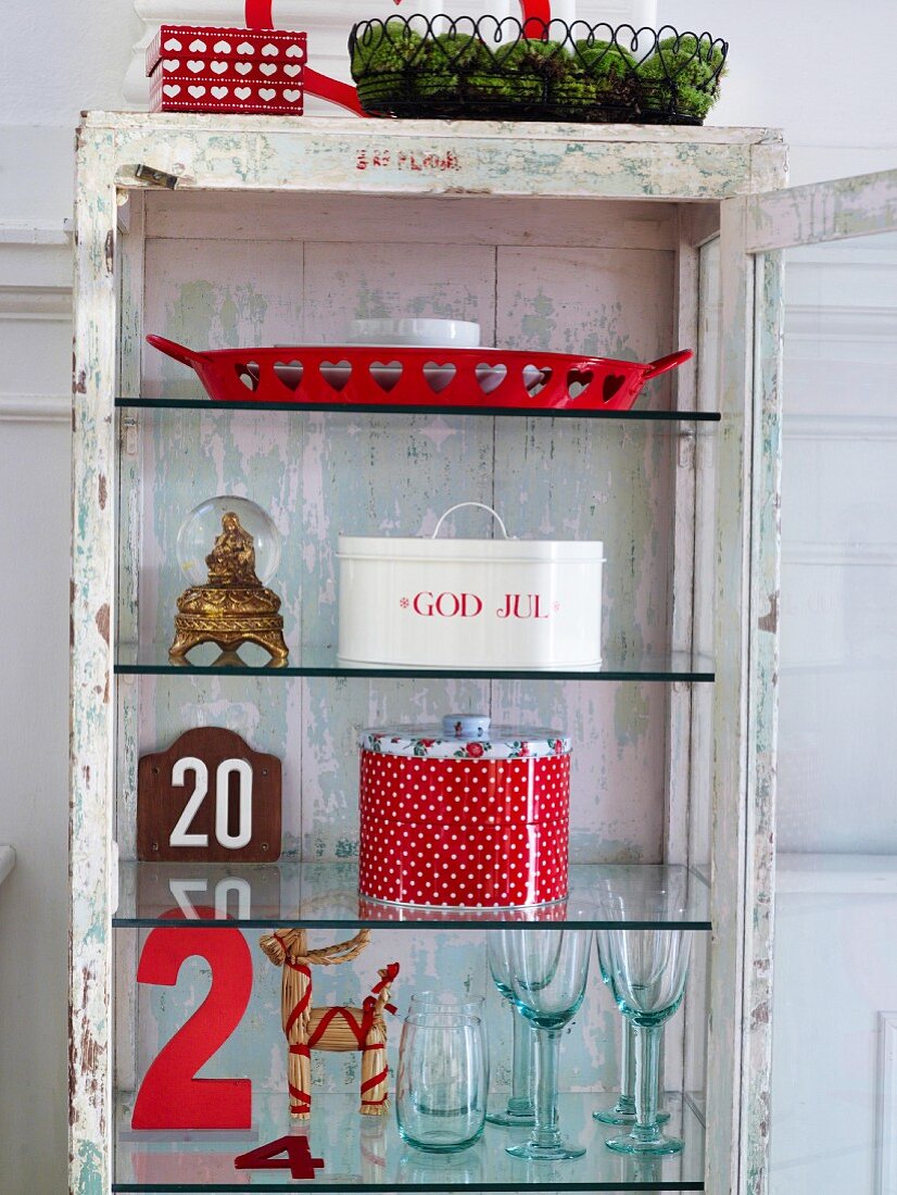 Open, glass-fronted cabinet with glasses & Christmas decorations