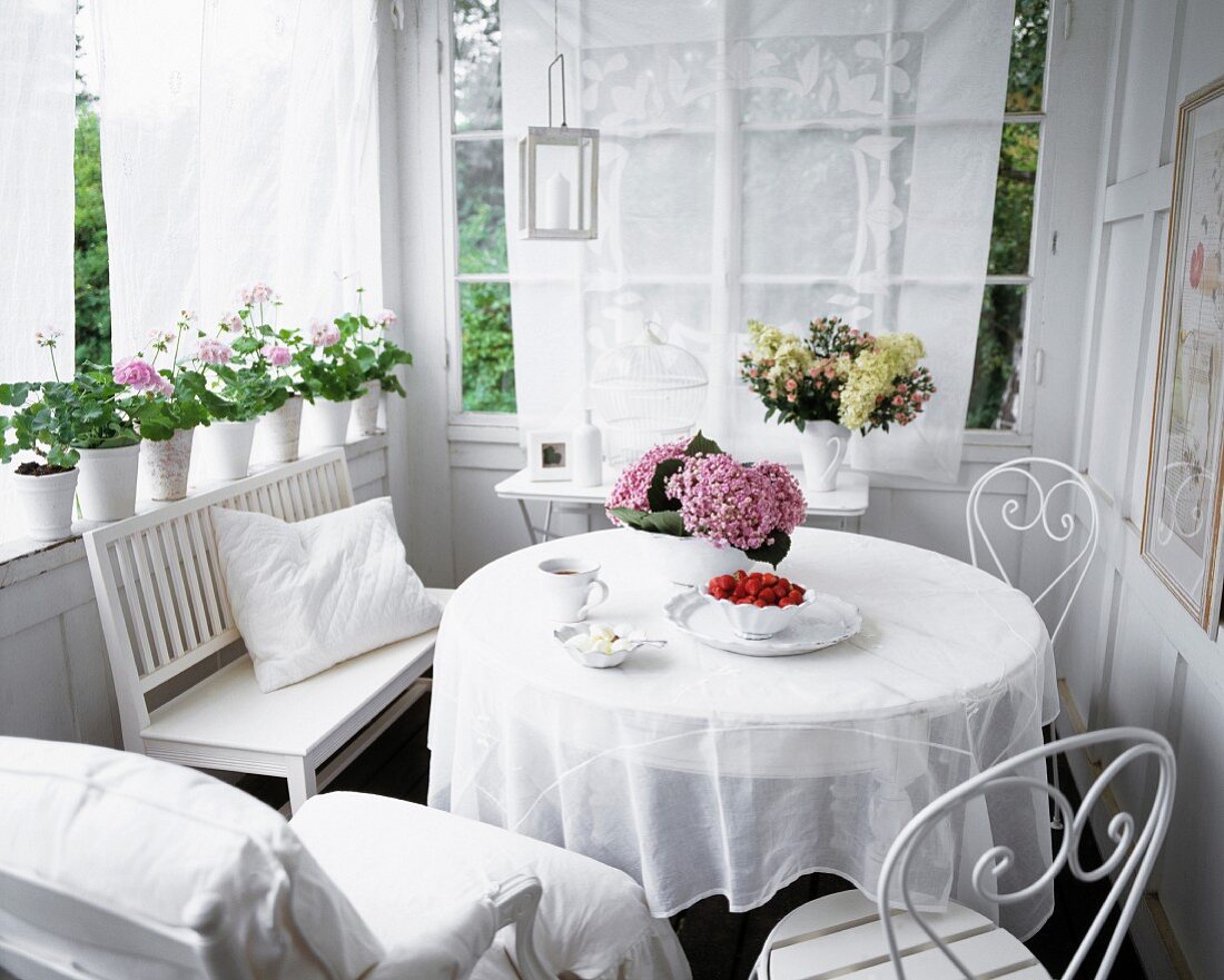 Runder Tisch mit Bank & Stühlen in Weiß auf Veranda