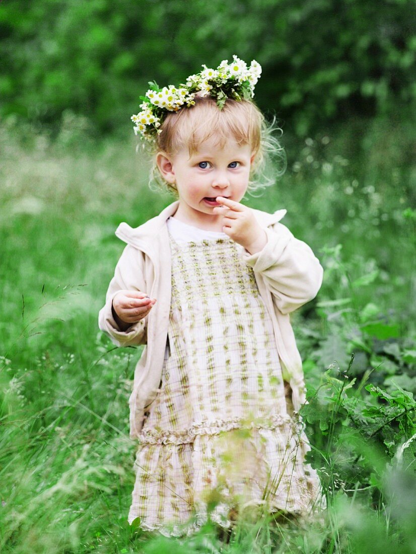Little girl in meadow wearing wreath of flowers