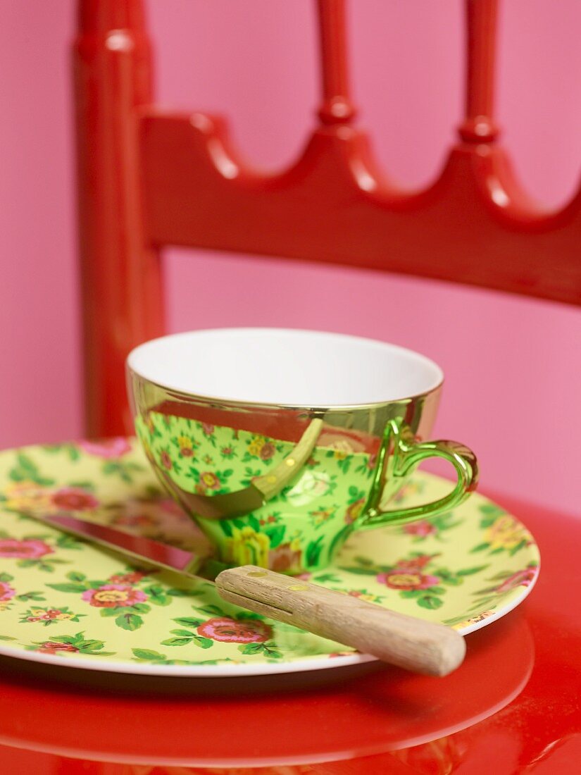 Reflektierende Teetasse auf Teller mit Blumenmotiv