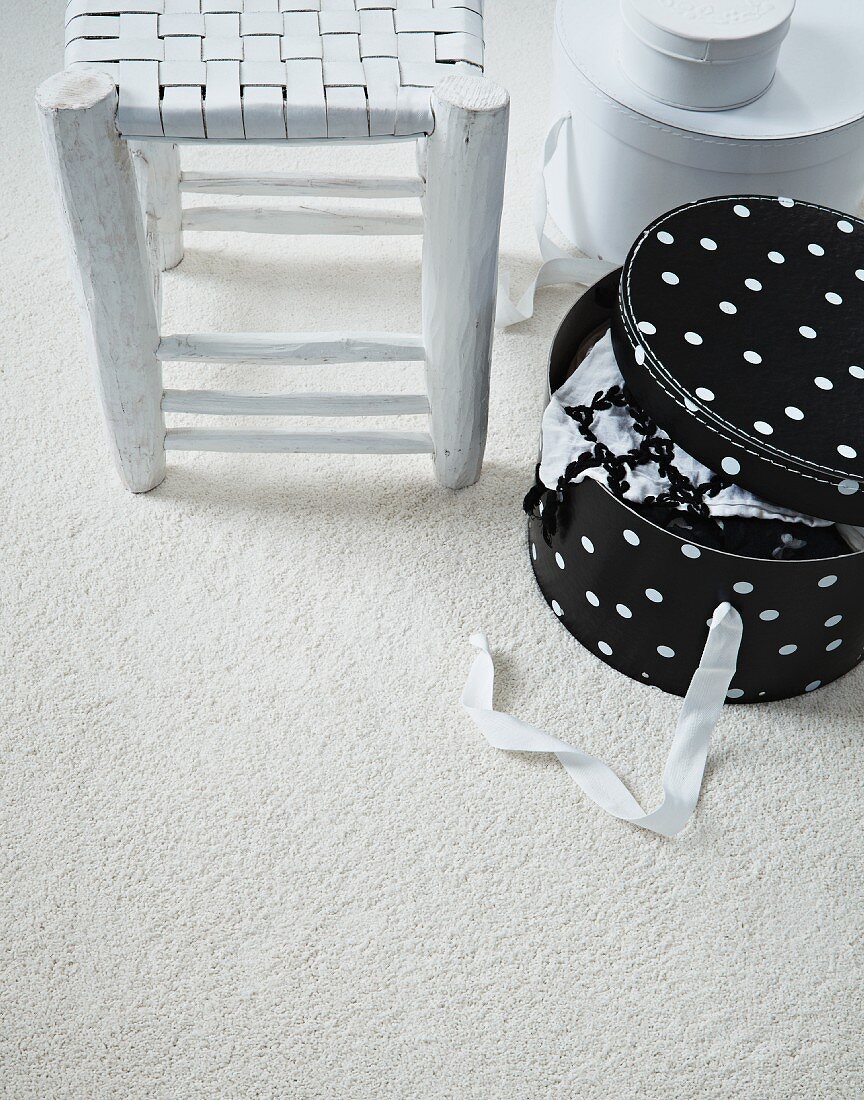 Flechthocker im Shabby Stil und Hutschachtel mit Pünktchenmuster auf weißem Teppichboden