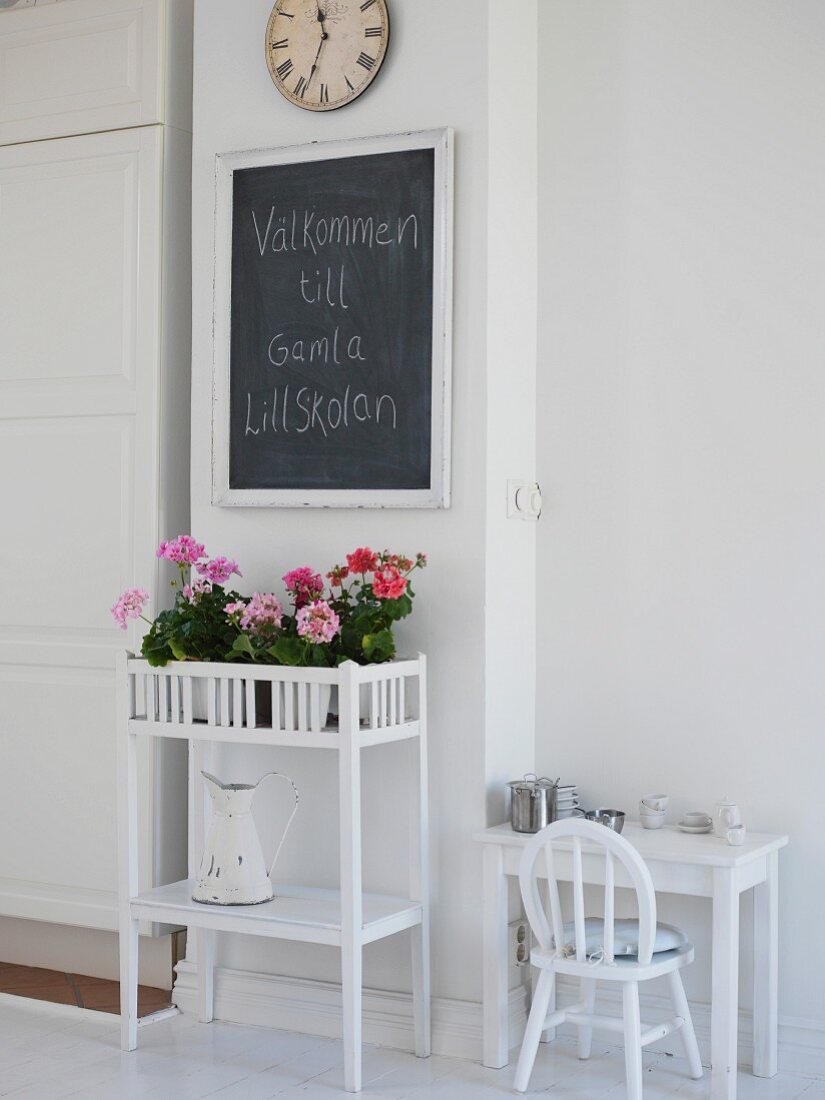 Flowers on plant stand & greeting written on chalkboard in foyer