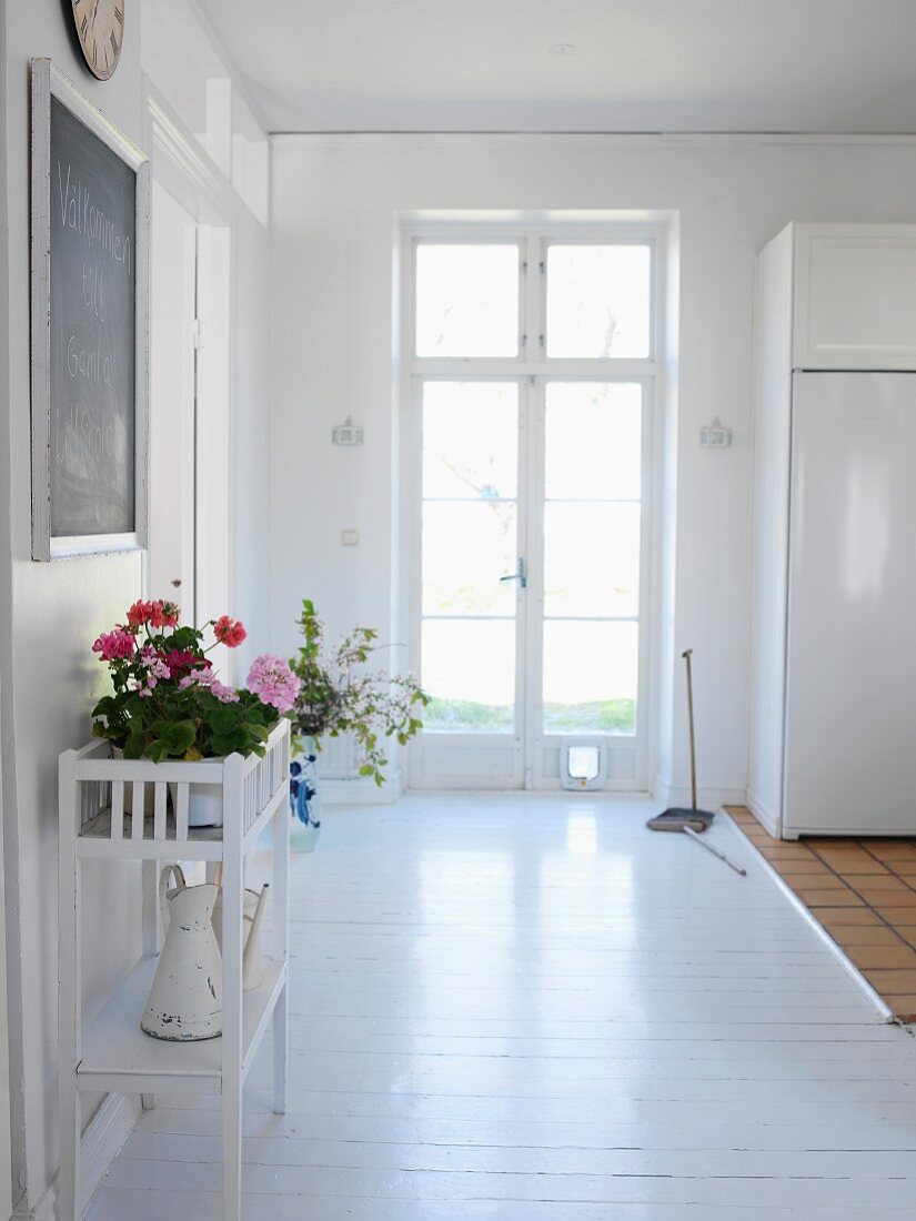 White foyer with front door & flowers on table