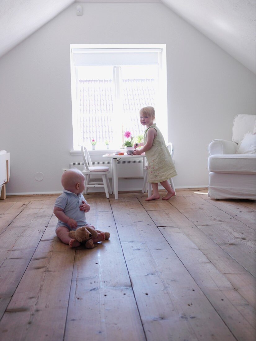 Kleines Mädchen & Kleinkind spielen auf ausgebautem Dachboden