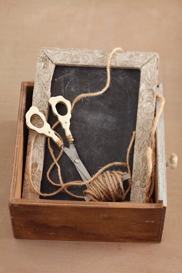 Slate, scissors and string in wooden drawer