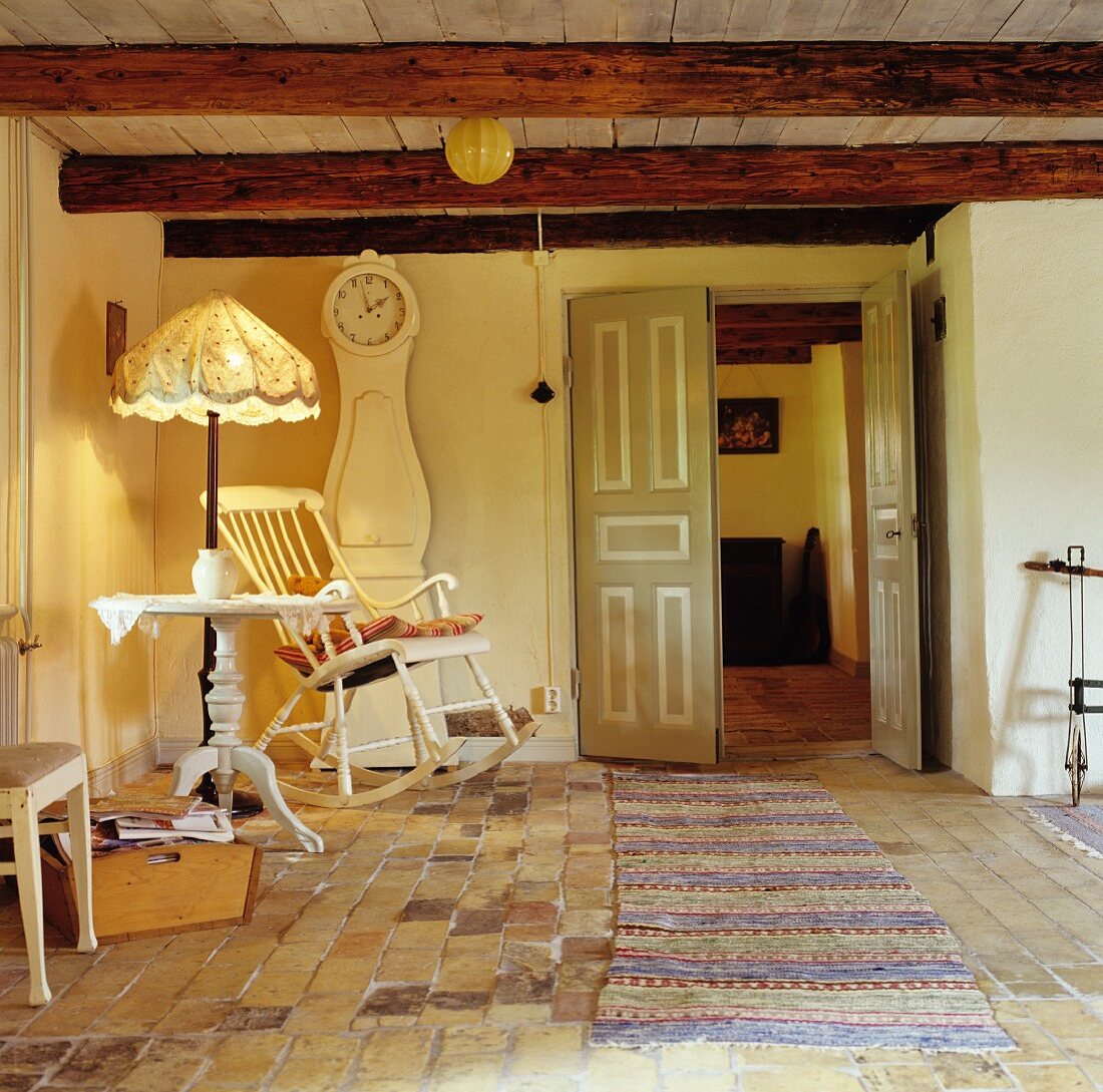 Wohnstube mit original Ziegelfliesen in altem, renovierten Bauernhaus; Sitzecke mit Schaukelstuhl und Standuhr