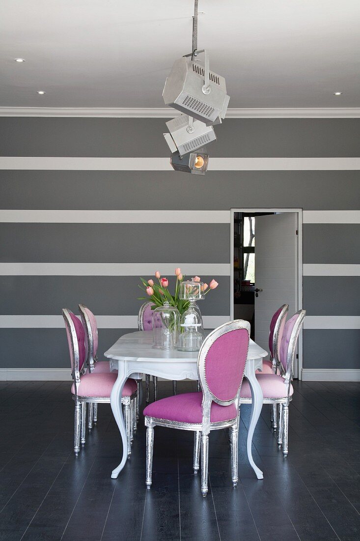 Neo Rokoko Stühle in Silber und Pink um Esstisch, dahinter grauweiss gestreifte Wand in elegantem, minimalistischem Ambiente