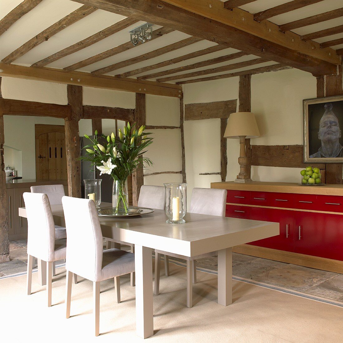 Simple, modern dining area with red sideboard in renovated half-timbered house