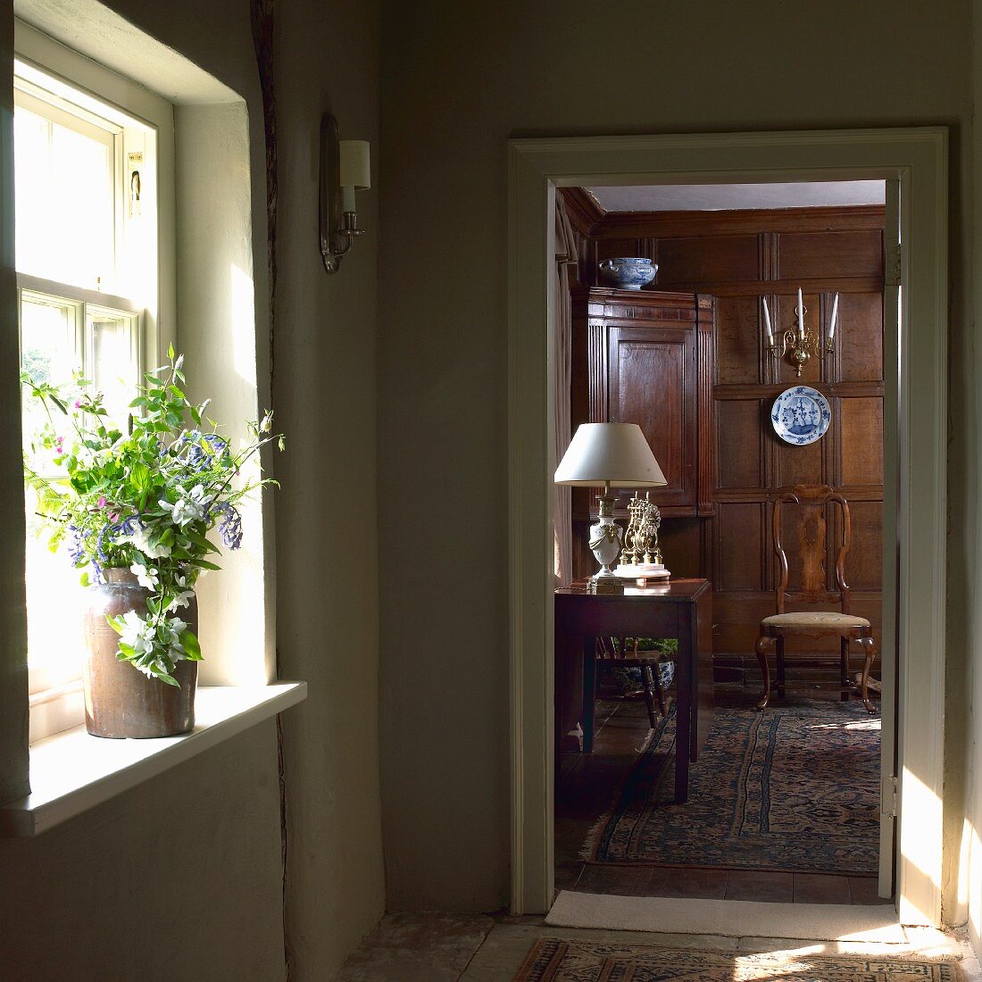 Blick durch offene Zimmertür auf gediegenen Wohnraum mit dunkler Holzvertäfelung