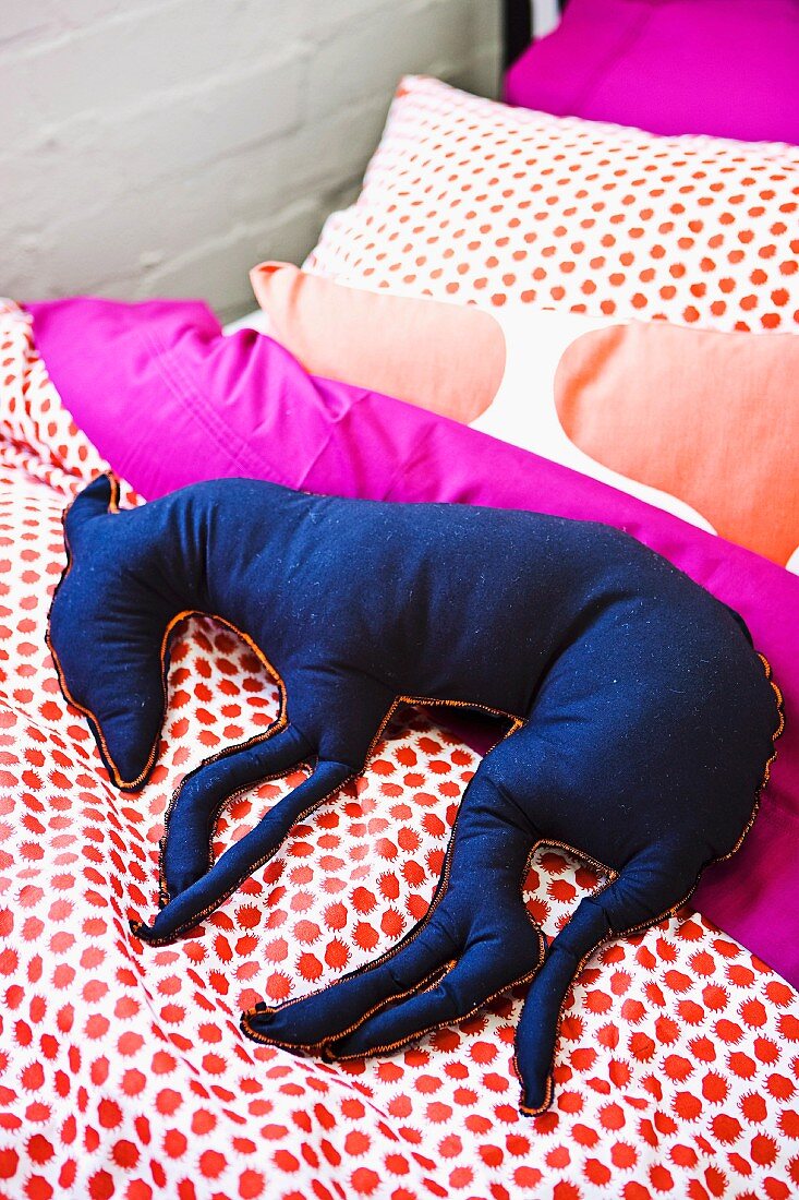 Blauer Stoffhund auf Bettdecke mit gepunktetem Muster