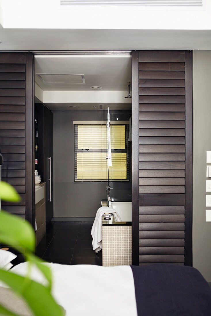 Elegant, masculine ensuite bathroom with dark brown, sliding louver doors
