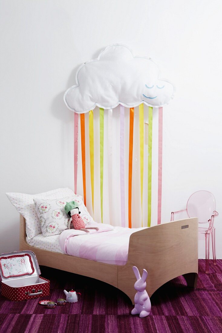 Child's bedroom with child's bed & cloud with ribbon rain decorating wall