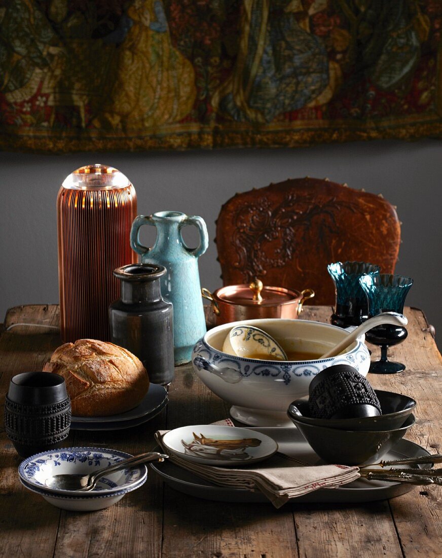 Eclectic collection of soup tureens, bowls, glasses and vases on rustic wooden table