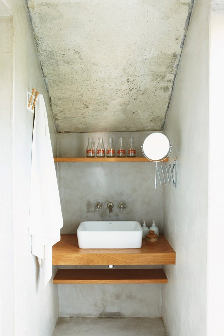 Narrow niche with washstand in house with exposed concrete walls