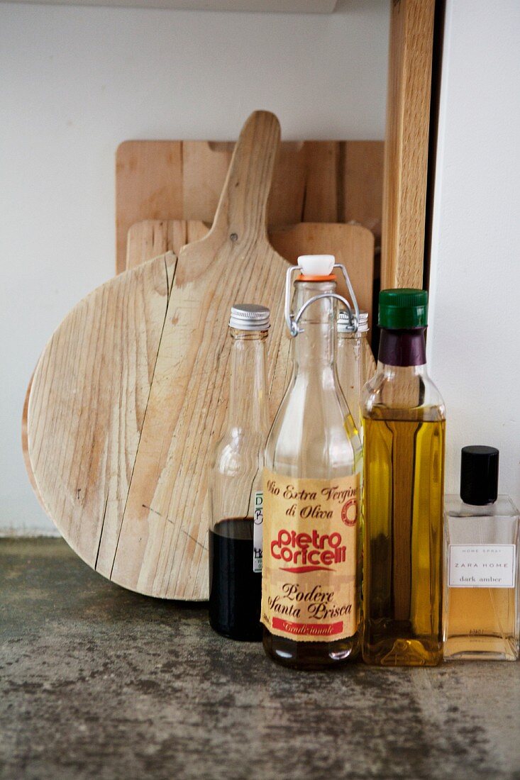 Vintage, swing-top bottle and bottles of vinegar and oil in front of wooden chopping boards