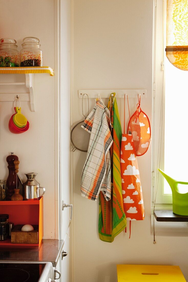 Wandhakenleiste mit bunten Geschirrtüchern in Küchenecke neben Fenster
