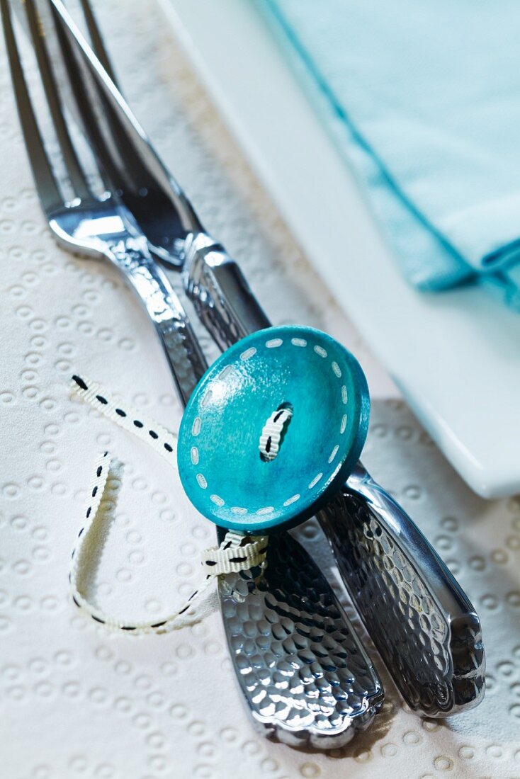 Cutlery tied together with ribbon and large button