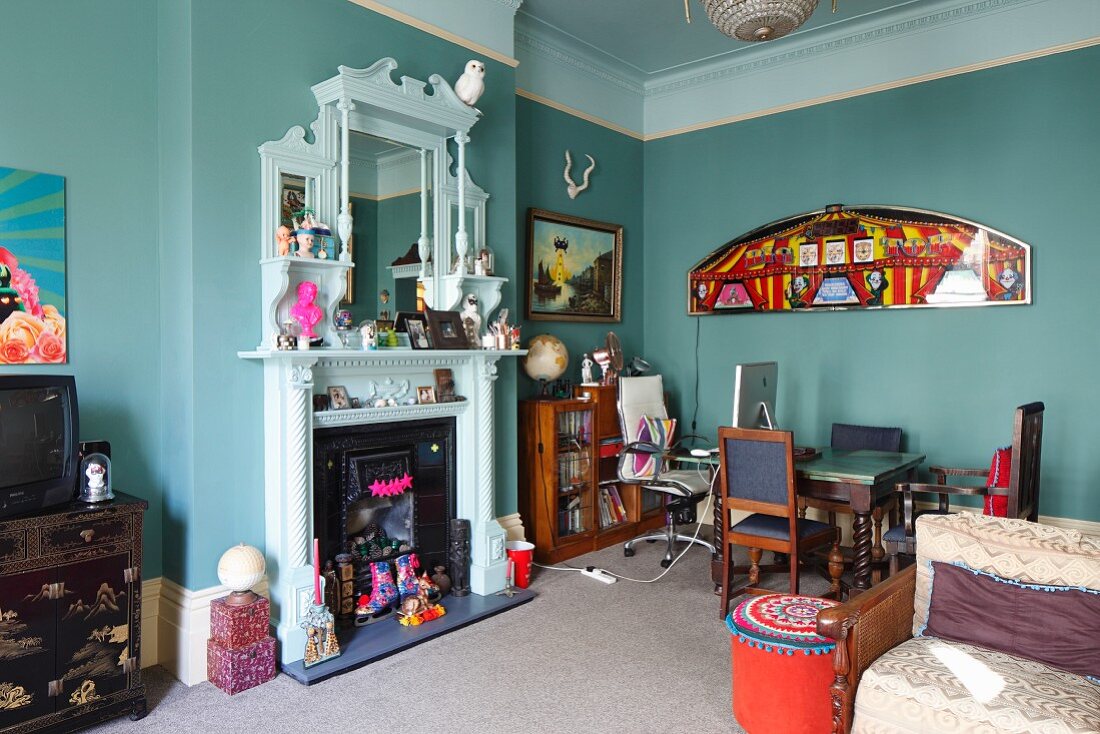 White-painted, nostalgic fire surround with mirror decorated with hotchpotch of flea market finds in open-plan living area