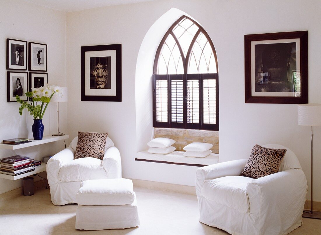 Sessel und Schemel mit weisser Husse in Zimmerecke vor Fensternische im gotischen Stil mit eingebauter Sitzbank