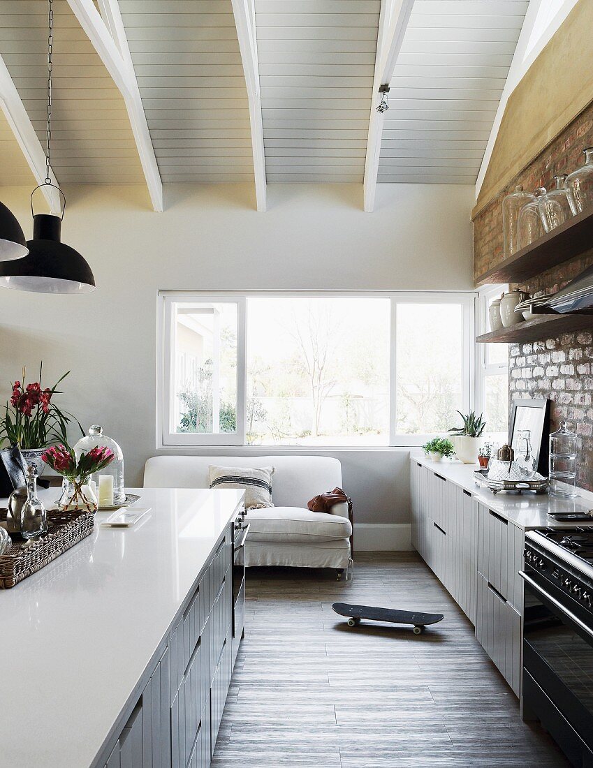 Offene Wohnküche im eleganten Landhausstil mit Sichtmauerwerk und Vintageflair an der Küchenwand