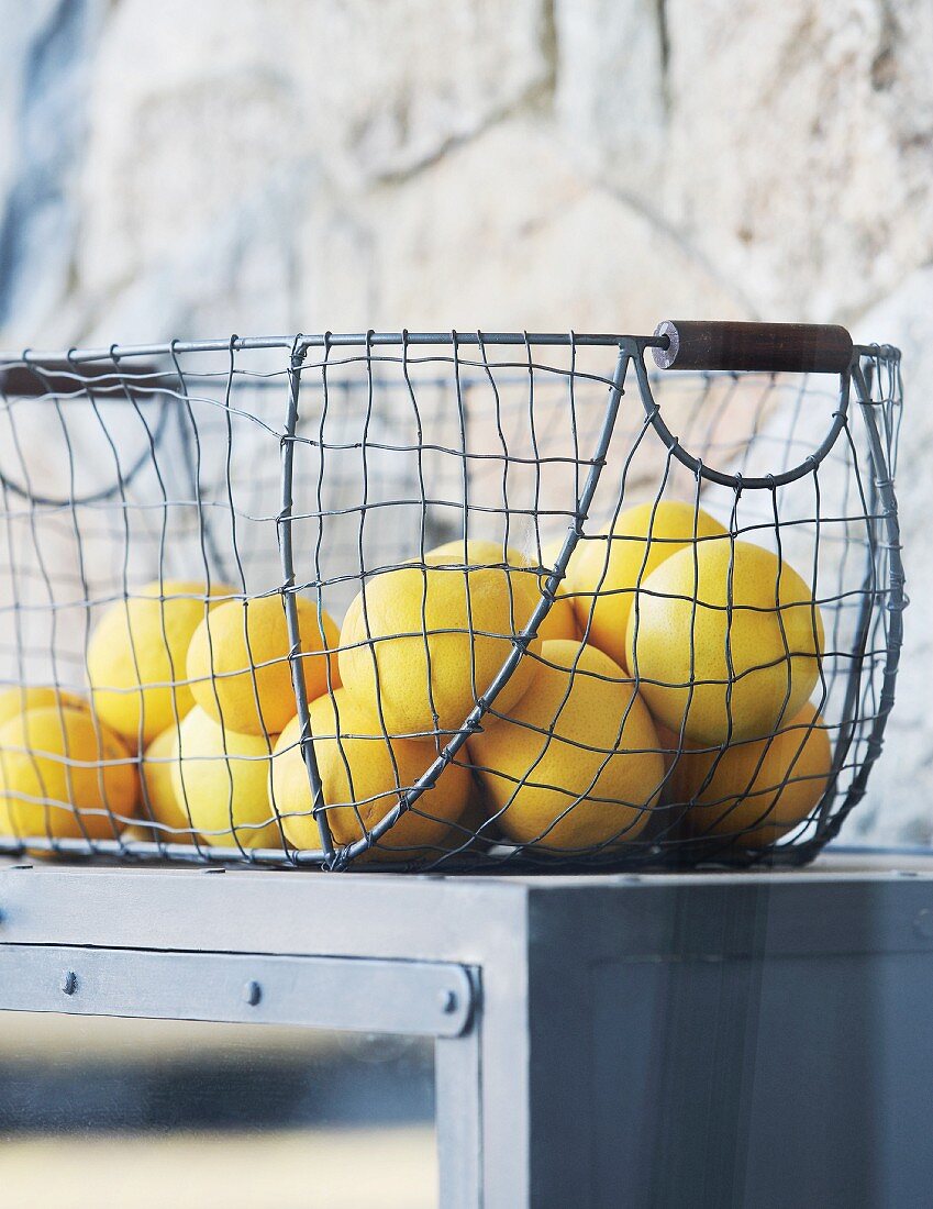 Zitronen in Vintage Drahtkorb auf grauem Küchenregal