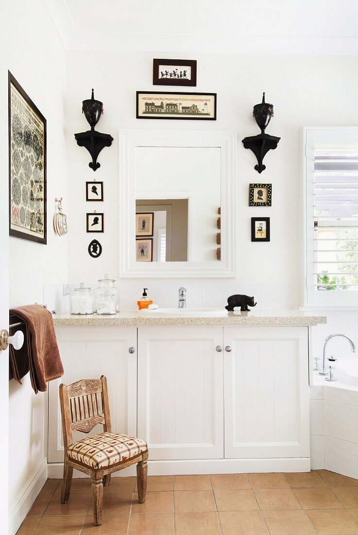 Bathroom with white washstand, bathroom mirror & small pictures and brackets decorating walls