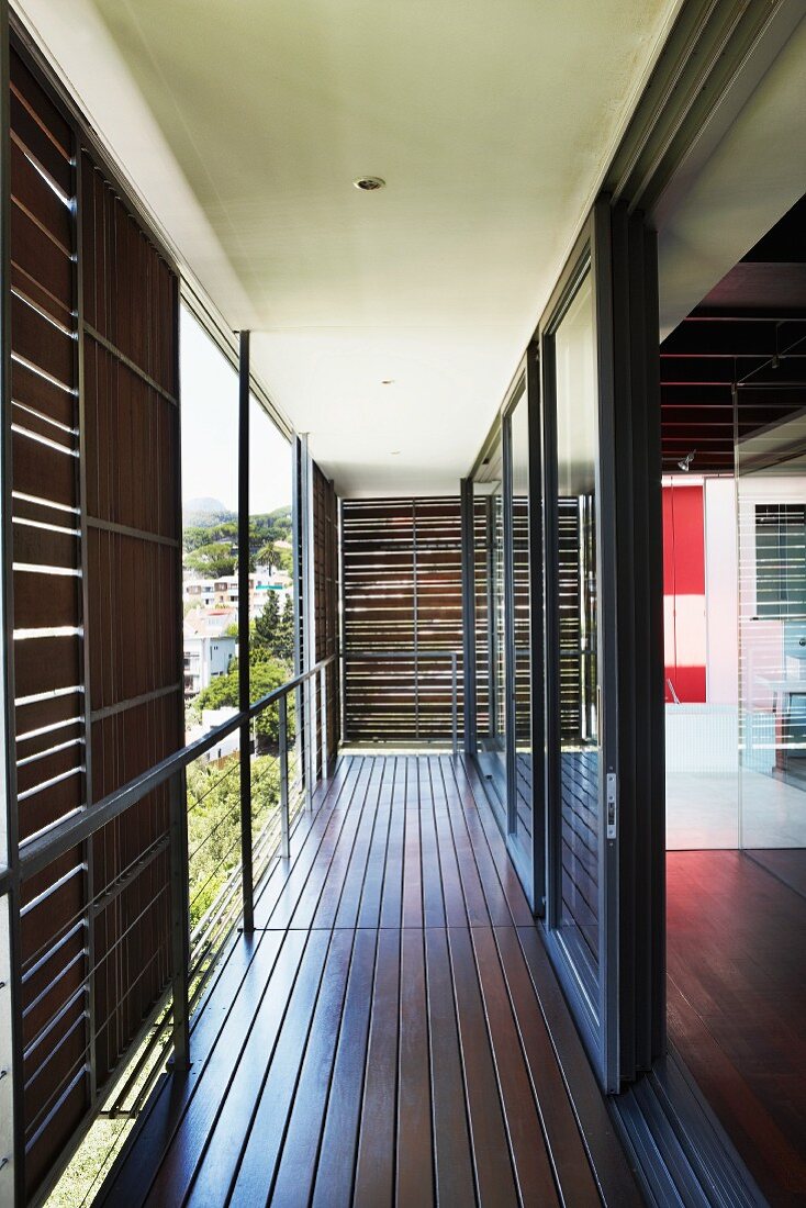 Balkon mit verschiebbaren Sonnenschutzpaneelen und langer Glasfront