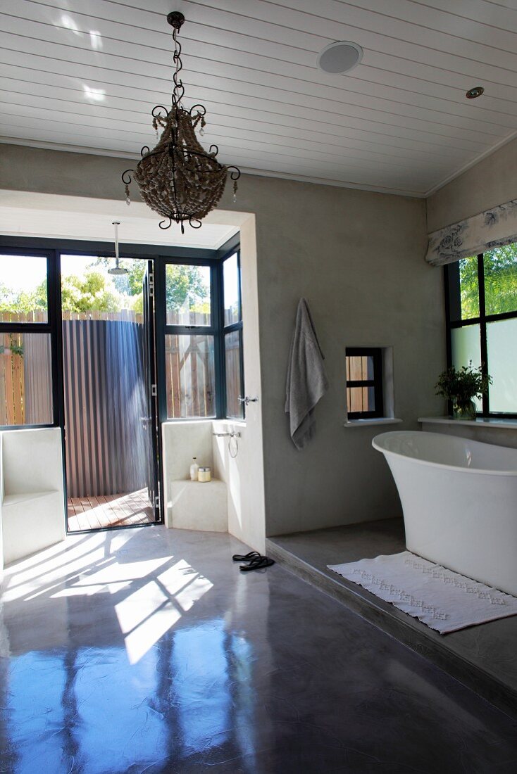 Large bathroom with free-standing bathtub on platform and terrace door