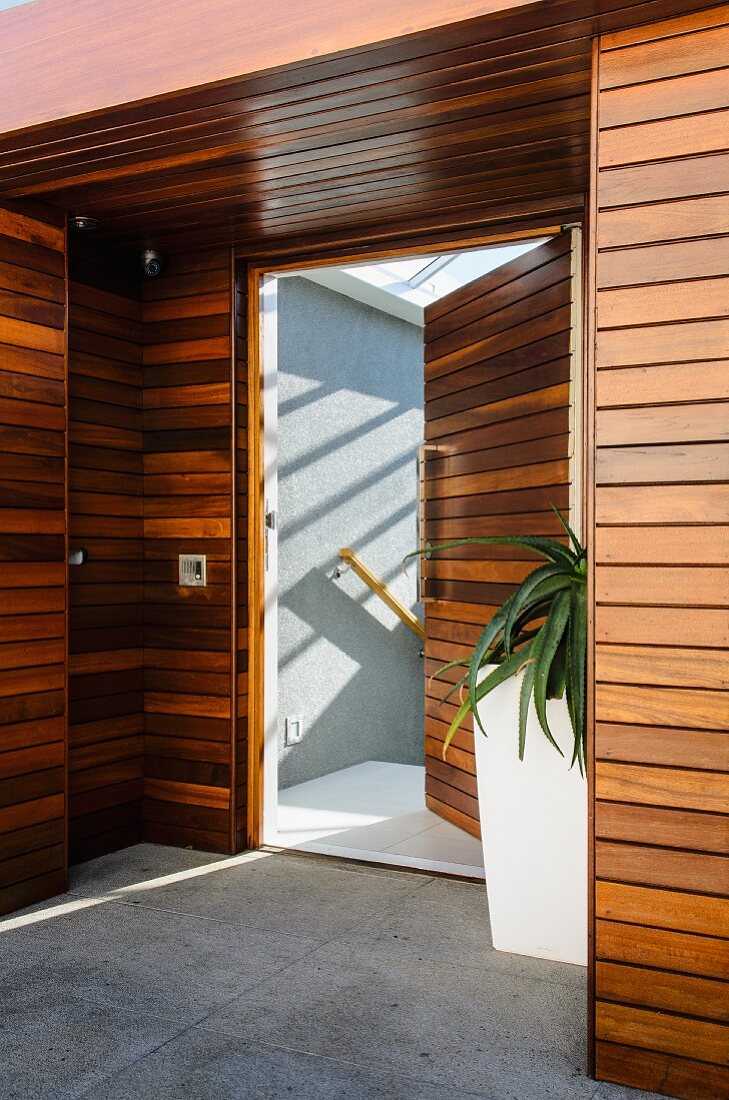 Wood-panelled foyer with large planter and open door leading to stairwell