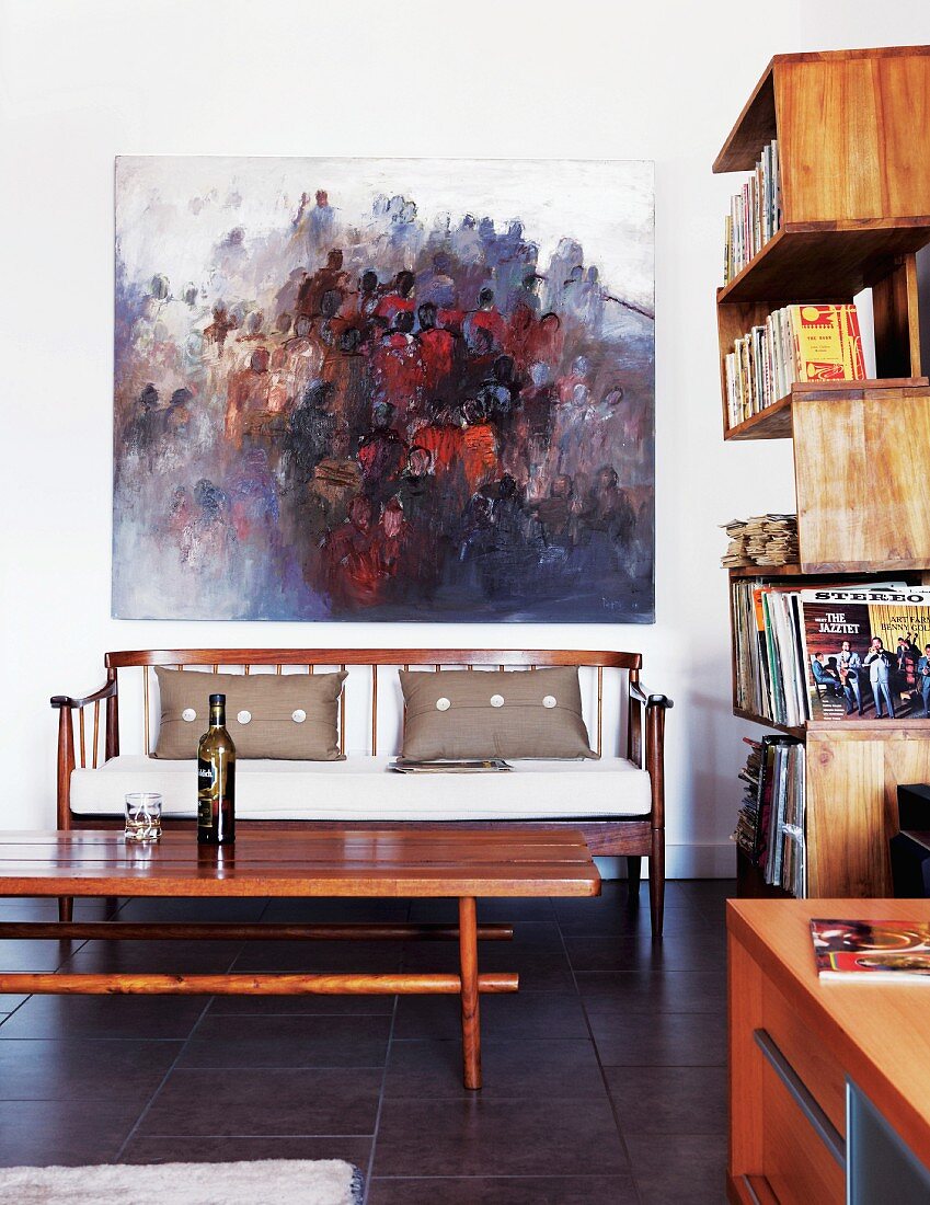 Modern oil painting over elegant wooden sofa; winding bookshelves on wall